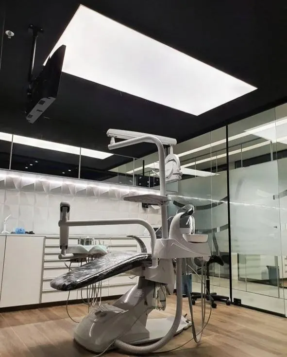 Clínica odontológica com tela tensionada iluminada no teto